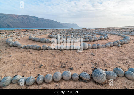 Completamente circolare pietre sul terreno formante una spirale vicino alla spiaggia, con Lanzarote in background, Caleta del Sebo, Graciosa, Canary Islan Foto Stock