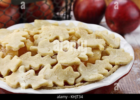 Raw, crudi la torta di mele con crosta superiore tagliata a forma di foglie di autunno. shallow morte del campo con il fuoco selettivo sul primo piano. Foto Stock