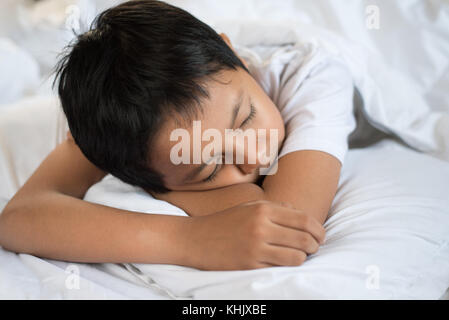 Bambino addormentato sul letto con foglio bianco e cuscino.asian kid addormentarsi fantasticando.concetto del sonno Foto Stock