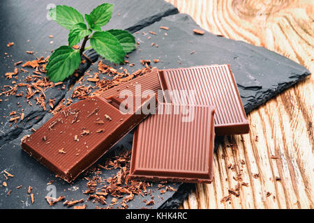 Rotture di cioccolato fondente e scaglie di cioccolato su un tavolo di legno Foto Stock