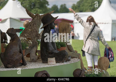 Close-up di sculture figurativo su Ann Hogben stand commerciali con una donna al di là - RHS Chatsworth flower show showground, Derbyshire, Inghilterra, Regno Unito. Foto Stock