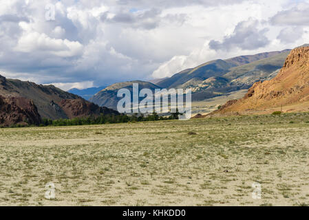 La steppa pittoresco paesaggio desertico con le montagne e la terra asciutta con rare piante su uno sfondo di Cielo e nubi Foto Stock