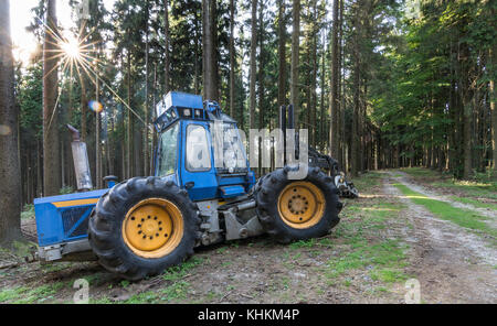 Mietitrice blu in una soleggiata estate legno. background industriale con registrazione macchina accanto a una strada forestale. Foto Stock