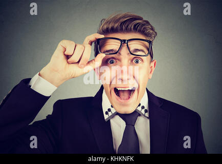 Sorpreso giovane uomo d affari tenendo di occhiali Foto Stock