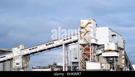 Un frammento di una moderna impresa industriale con diversi silos per lo stoccaggio di materiali sfusi e una coperta inclinata trasportatore a nastro Foto Stock