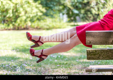 Coppia donna seduta su un tavolo in un giardino e gambe penzolanti Foto Stock