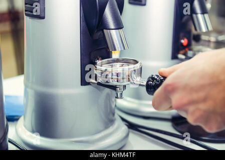 Close up barista prendere caffè macinato in gruppo, preparare per la produzione di birra colpo espresso. Il fuoco selettivo. spazio per il testo. Foto Stock