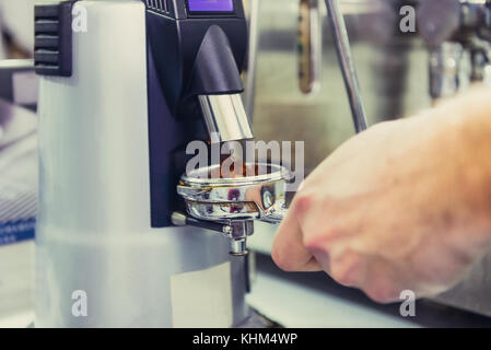 Close up barista prendere caffè macinato in gruppo, preparare per la produzione di birra colpo espresso. Il fuoco selettivo. spazio per il testo. Foto Stock