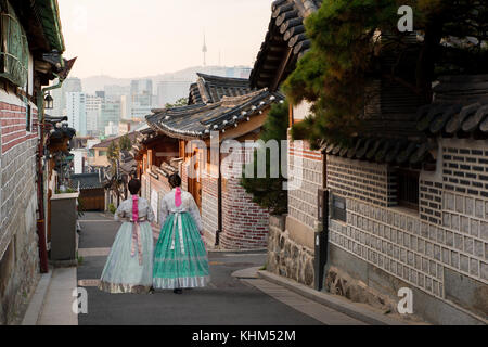 Indietro di due donne che indossano hanbok camminando attraverso lo stile tradizionale delle case di il villaggio di Bukchon Hanok a Seul, in Corea del sud. Foto Stock