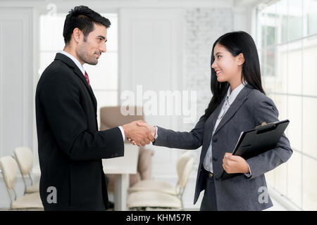 Successo del lavoro asian imprenditore e imprenditrice stringono le mani in sala consiglio al termine di una riunione. Foto Stock