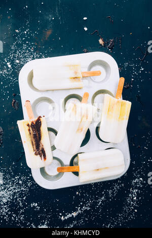 Annuncio yougurt mango popsicles su uno stampo di alluminio per muffin Foto Stock