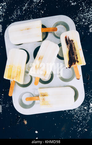 Annuncio yougurt mango popsicles su uno stampo di alluminio per muffin Foto Stock