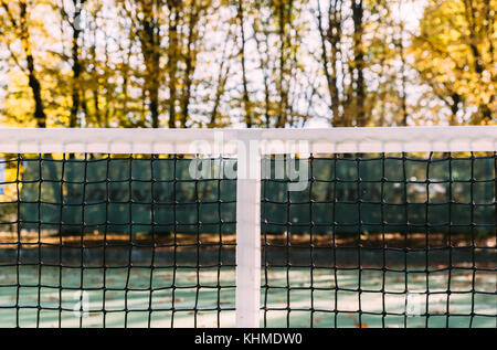 Primo piano della rete da tennis nel fogliame autunnale Foto Stock