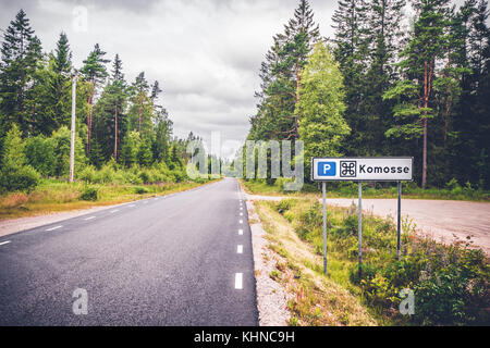 Komosse riserva naturale in Svezia con un segno da parte di un apshalt road nel mezzo di una foresta svedese Foto Stock