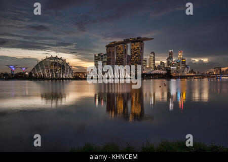 Lo skyline di Singapore si riflette nella Marina Bay, con supertrees, il cloud computing e le cupole di fiori, marina bay sands e il quartiere finanziario, il tutto sotto un moody Foto Stock