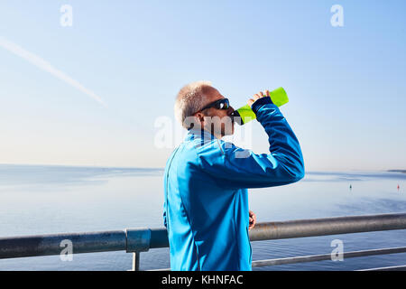 Sete sportivo di bere acqua fresca da bottiglia di plastica in ambiente naturale Foto Stock