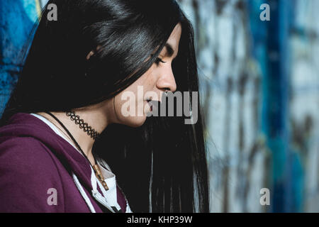 Un stile grunge e dai capelli scuri donna con un cappuccio Felpa viola Foto Stock