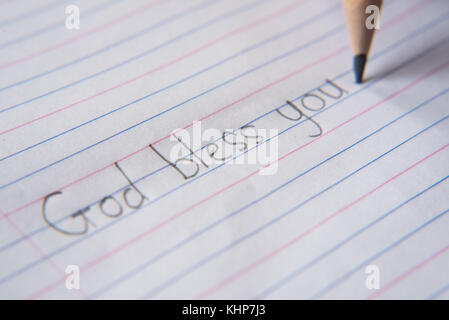 Scrittura a mano utilizzando una matita su un foglio di carta.scrivere " Dio vi benedica" Foto Stock