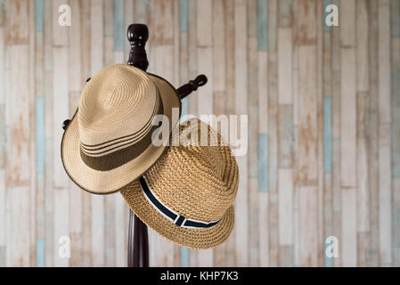 Cappello di paglia appesi su appendiabiti in legno.Accessori per abbigliamento e concetto di viaggio Foto Stock