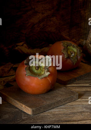 Vista superiore kaki sul tavolo di legno e castagne Foto Stock