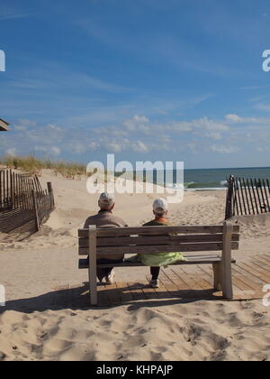 Coppia di anziani godendo il sole su un New Jersey seaside banco. Foto Stock