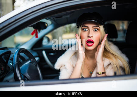 Distratti spavento volto di una donna alla guida di auto, ampia bocca aperta occhi holding lato ruota la visualizzazione della finestra. negativo faccia umana espressione emozione reazione. t Foto Stock