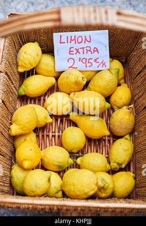 Limoni ecologico in un cesto di vimini di un mercato. (Cartello in spagnolo che mostra il prezzo) Foto Stock