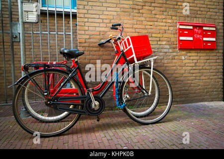 Tradizionali olandesi biciclette parcheggiate sul vicino a un muro di mattoni in Amsterdam Foto Stock