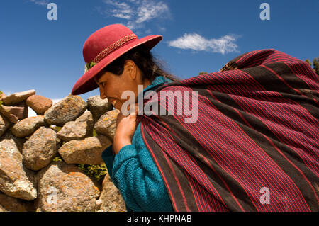 Una donna torna a casa dopo una dura giornata in campagna sull'isola di Amantani. Isola Amantani, lago Titicaca, Puno, Perù Foto Stock