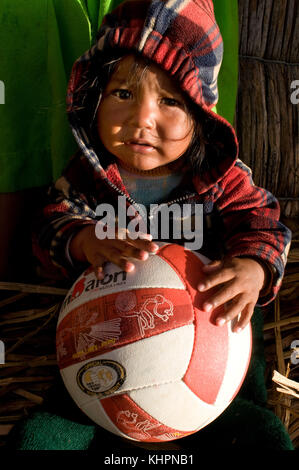 Isola di Uros, lago Titicaca, perù, Sud America. Una ragazza sull'isola di Los Uros, situata all'interno del lago Titicaca, gioca a pallavolo. Foto Stock