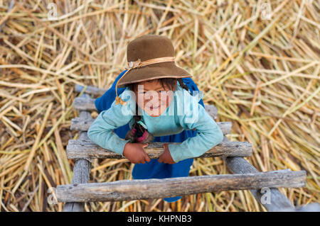 Isola di Uros, lago Titicaca, perù, Sud America. Una ragazza sull'isola di Los Uros situata all'interno del lago Titicaca gioca a salire su una scala. Foto Stock