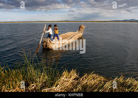 Isola di Uros, lago Titicaca, perù, Sud America. I bambini navigano in una barca totora sul lago Titicaca vicino a un'isola abitata da Uros. Foto Stock