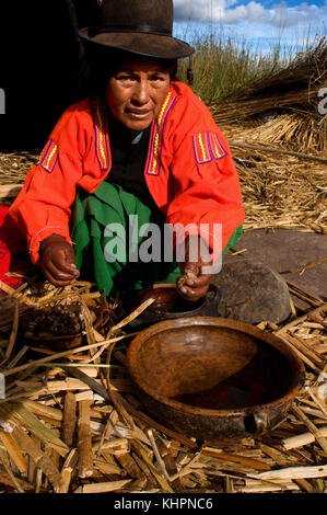 Isola di Uros, lago Titicaca, perù, Sud America. Una donna prepara la colazione sull'isola di Los Uros situata all'interno del lago Titicaca. Foto Stock