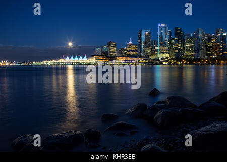 Bellissima vista del centro cittadino di Vancouver skyline durante la notte con la luna piena in aumento. prese nel Parco di Stanley intorno Coal Harbour, British Columbia, Foto Stock