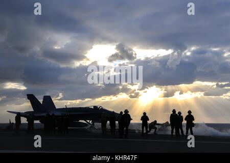 Un u.s. navy f/a-18c hornet jet da combattimento aereo decolla dal ponte di volo della marina degli Stati Uniti nimitz-class portaerei USS Theodore Roosevelt al tramonto novembre 11, 2017 nell'oceano pacifico. (Foto di spencer roberts via planetpix) Foto Stock