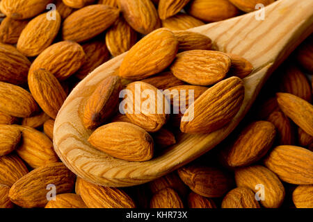 Cumulo di mandorle sgusciate i kernel cucchiaio di legno su sfondo di mandorla Foto Stock