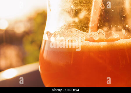 Frullato di arancione in vetro con paglia al tramonto Foto Stock