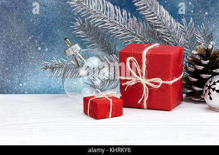 Regalo di natale scatole avvolte in carta di colore rosso con abete decorazioni contro sfondo blu Foto Stock