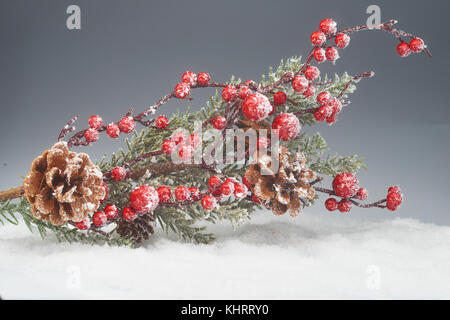 Natale decorazioni d'inverno. rami di abete rosso, coni, bacche rosse nella neve Foto Stock