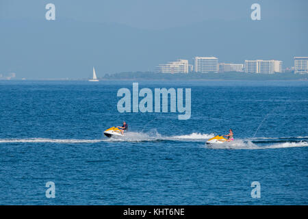 Messico, Stato Di Jalisco, Puerto Vallarta. Turisti a Banderas Bay su moto d'acqua con New Vallarta in lontananza. Foto Stock