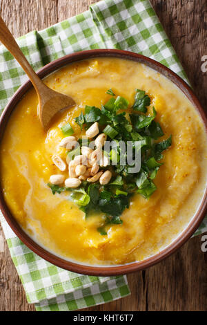 Thai curry di zucca minestra con noccioline e coriandolo vicino sul tavolo. verticale in alto vista da sopra Foto Stock