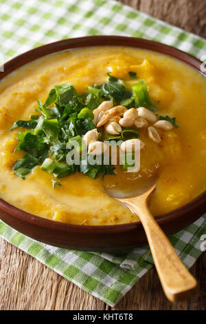 Thai curry di zucca minestra con noccioline e coriandolo vicino sul piano verticale. Foto Stock