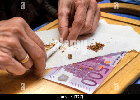 La marijuana preparazione congiunta sul tavolo accanto alle banconote in euro, indoor closeup Foto Stock