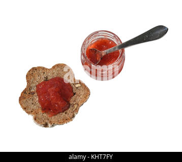 Pezzo di domestici, pane fatto in casa con cereali integrali e vaso piccolo con un delizioso wild confettura di fragole, isolato Foto Stock