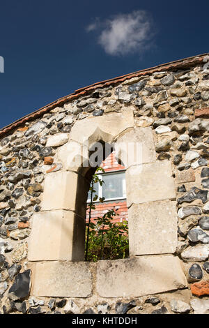 Regno Unito, Inghilterra, Norfolk, Thetford, Mill Lane, vecchia finestra di pietra adagiato nella tradizionale pietra focaia e muro di pietra Foto Stock