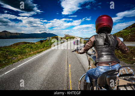 Biker ragazza scorre una strada di montagna in Norvegia oceano atlantico road. visuale in prima persona. Foto Stock