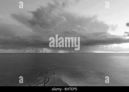 Tempesta di pioggia drammatica seascape con scala bagno sulla costa del mare adriatico, Istria, Croazia. in bianco e nero. Foto Stock