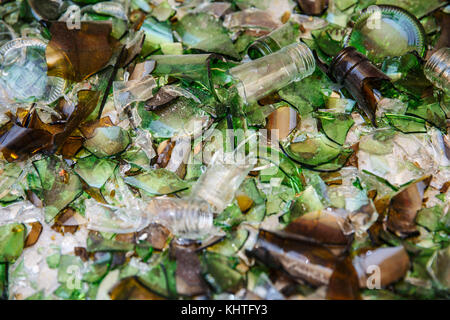 Cocci di bottiglie in vetro verde, sparsi sulla superficie bianca. Sfondo Foto Stock