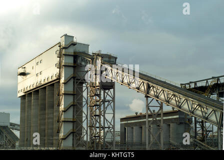 Frammento di una moderna impresa industriale con silos per lo stoccaggio di materiali sfusi e una coperta inclinata trasportatore a nastro Foto Stock