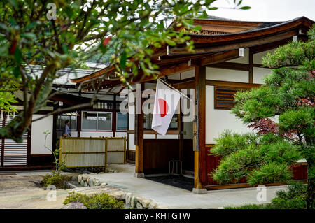 L'isola di Miyajima, Hiroshima, Giappone, ottobre 2017 Giapponese casa tradizionale con bandiera Foto Stock